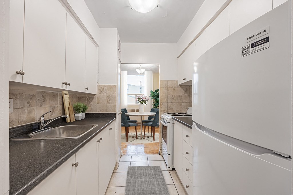 A kitchen with white cabinets and a black counter top.