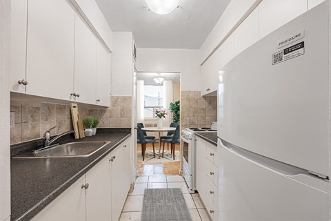 A kitchen with white cabinets and a black counter top.