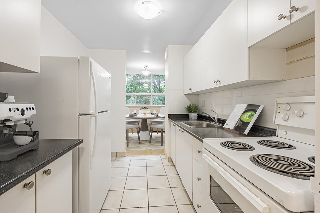A kitchen with white appliances and black countertops.