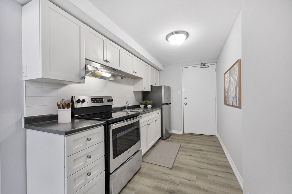 A kitchen with white cabinets and a stove top oven.