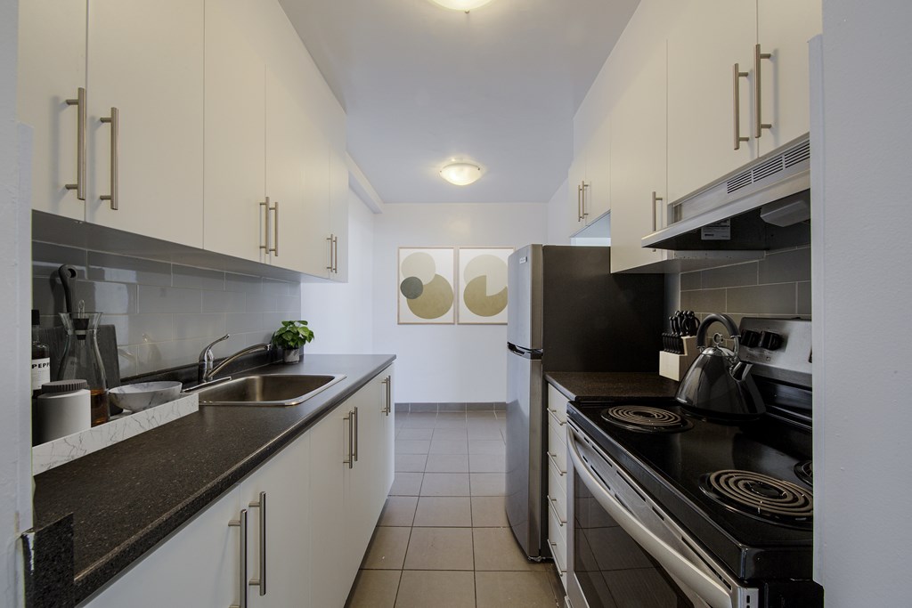 A modern kitchen with white cabinets and a black stove top.