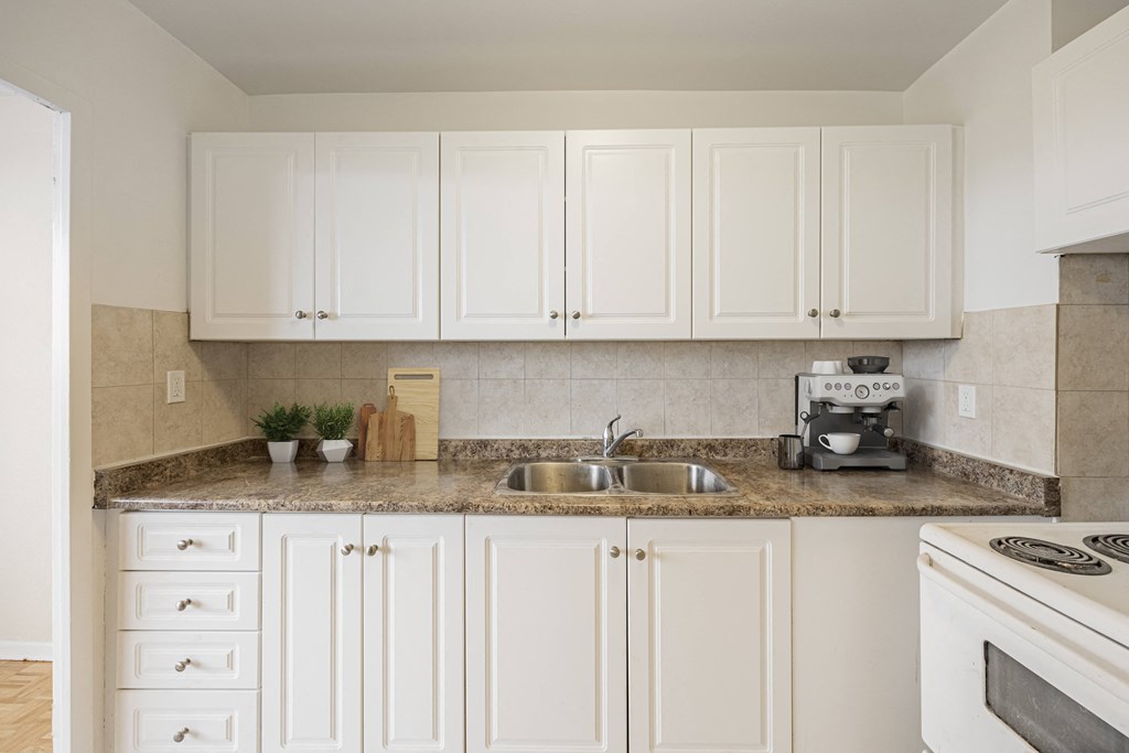 A kitchen with white cabinets and a granite countertop.