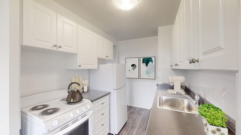 A white kitchen with a stove, sink, and cabinets.