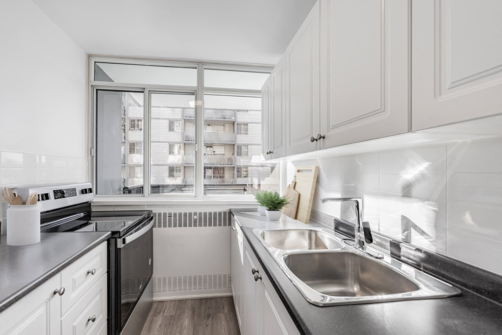 A modern kitchen with a stainless steel sink and a window overlooking a building.