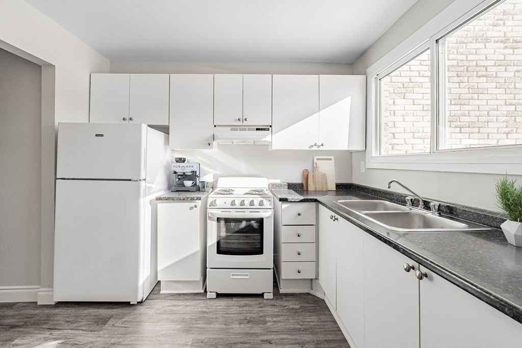A white kitchen with a refrigerator, oven, and sink.