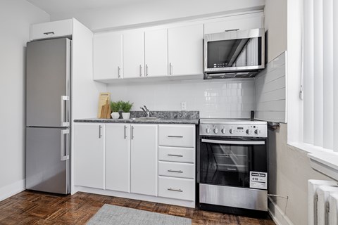 A modern kitchen with a stainless steel refrigerator, oven, and microwave.