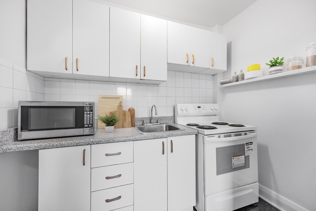 A white kitchen with a microwave, sink, and stove.