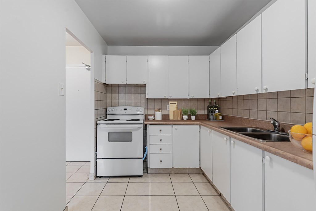 A kitchen with white cabinets and a white oven.