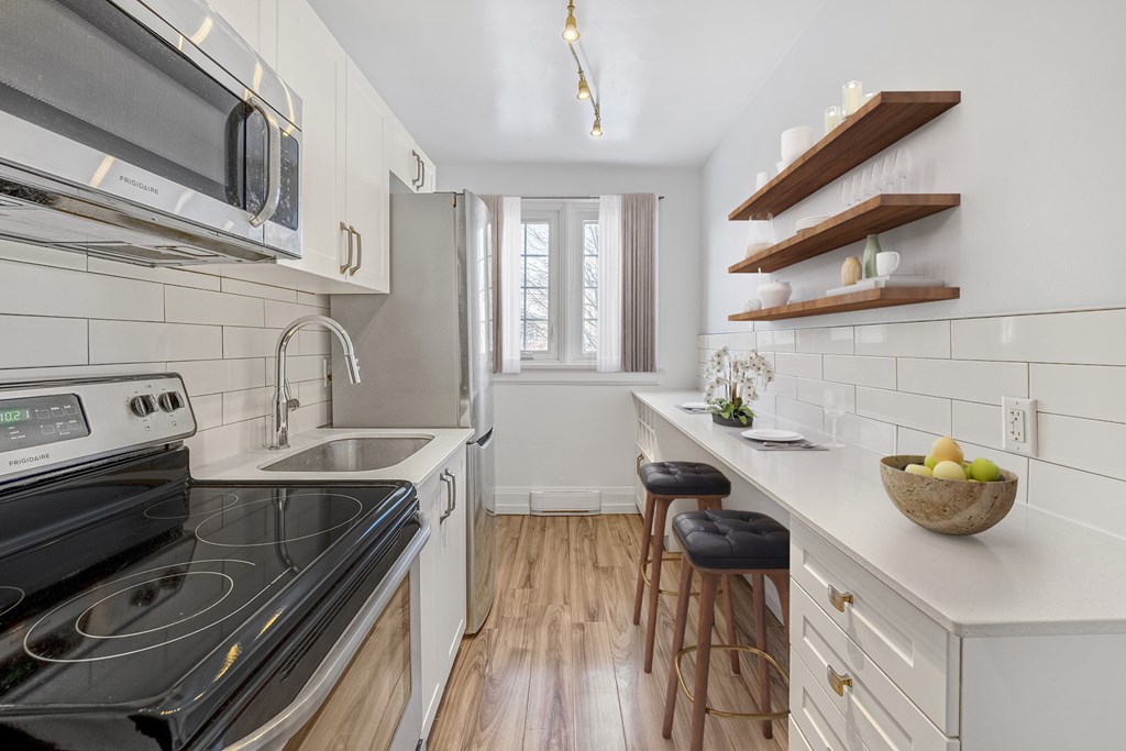 A modern kitchen with a black stove top oven and white cabinets.