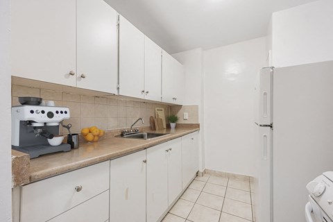 A kitchen with white cabinets and a white refrigerator.