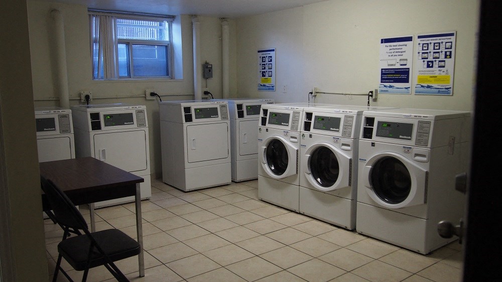 A laundry room with a row of washers and dryers.