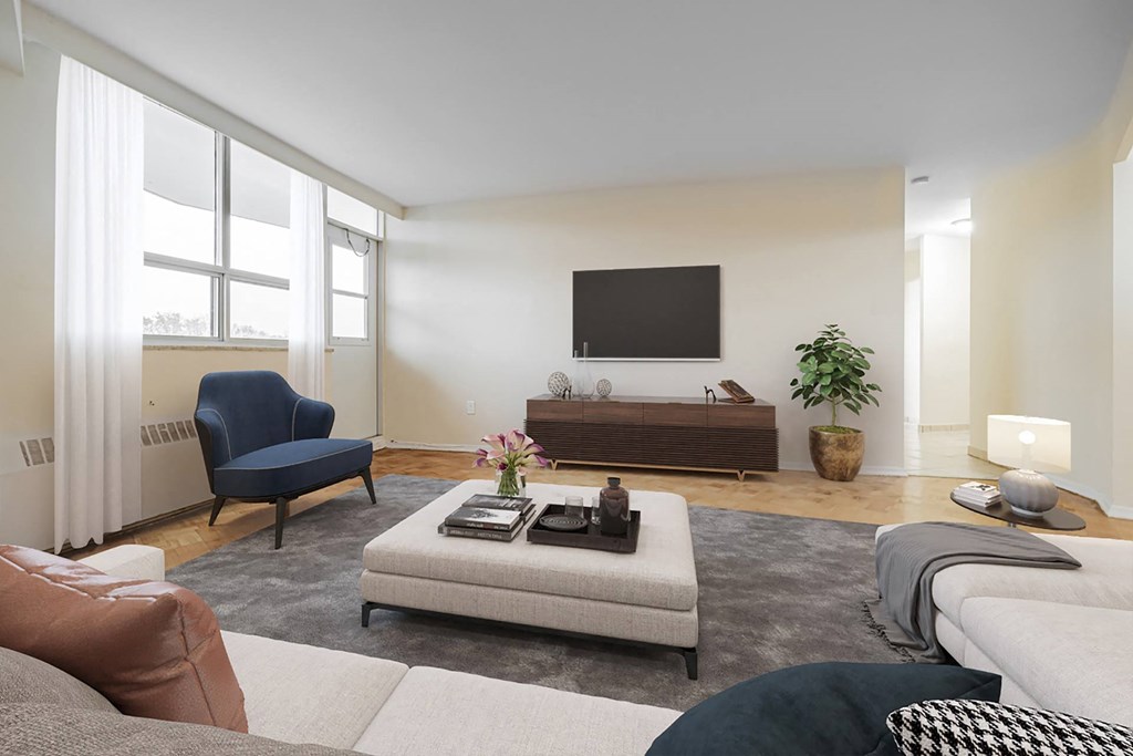 A living room with a blue chair, a grey sofa, a white couch, and a television on the wall.