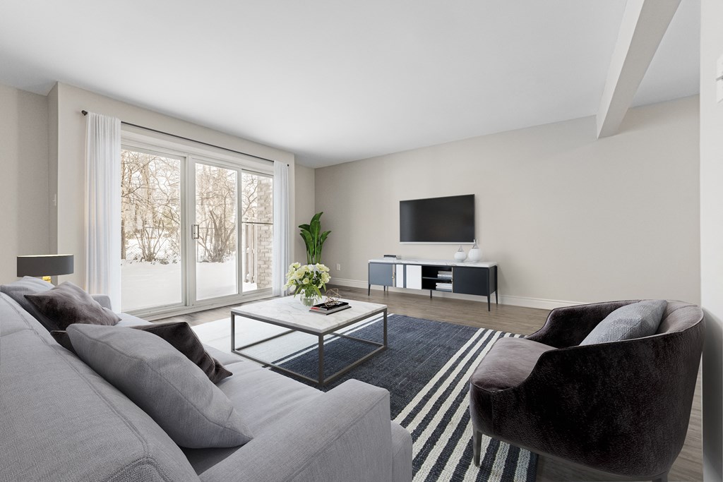 A living room with a grey couch, a black chair, and a television.