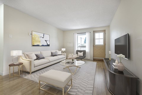 A living room with a white couch, a coffee table, and a television.