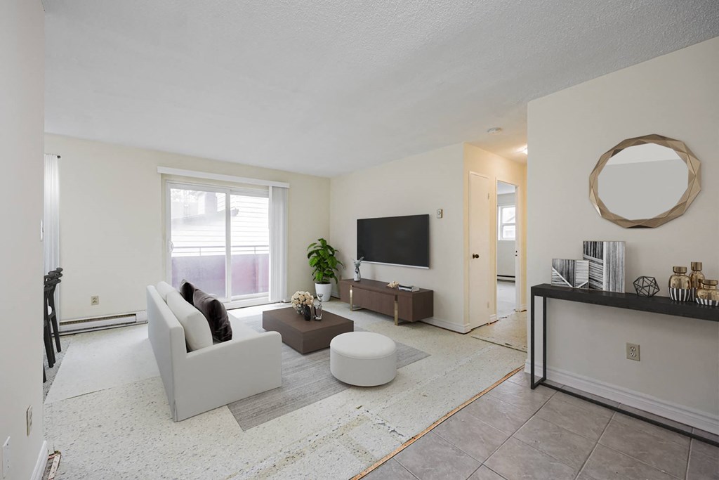 A living room with a grey couch, a brown coffee table, and a flat screen TV mounted on the wall.