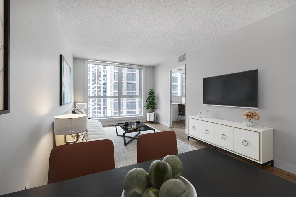 A living room with a television, a couch, a chair, a table, and a potted plant.