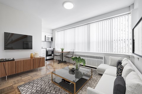 A modern living room with a flat screen TV, a glass coffee table, and a grey sofa.