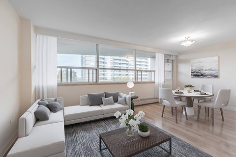 A living room with a white couch, a coffee table, and a dining table set up.