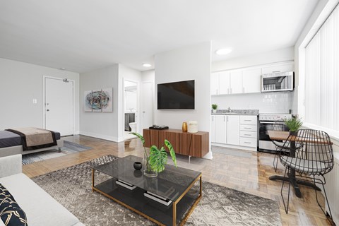 A modern living room with a glass coffee table and a TV on the wall.