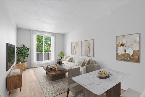 A living room with a white sofa, a wooden coffee table, and a large window with a view of greenery outside.