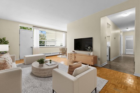 A living room with a white sofa, a coffee table, a television, and a plant.