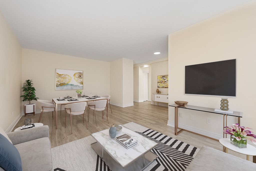 A living room with a grey sofa, a white coffee table, and a television on the wall.