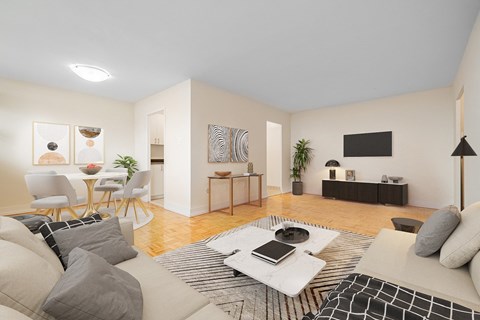 A living room with a white couch, a coffee table, and a TV on the wall.