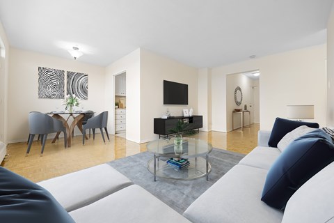 A living room with a white couch and a glass coffee table.