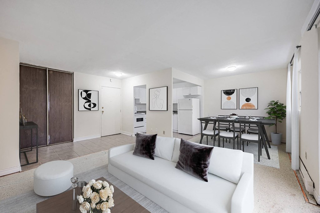 A white couch with a pillow and a vase of flowers on a coffee table in a modern living room.