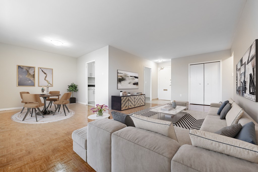 A living room with a grey couch and a round table with chairs.