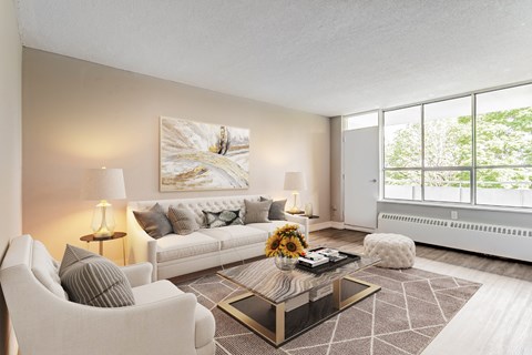 A modern living room with a white sofa, two chairs, a coffee table, and a large painting on the wall.