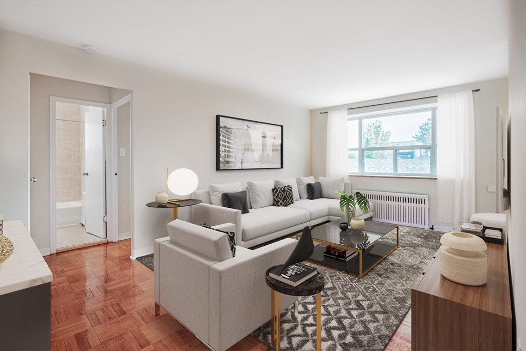 A living room with a white couch, a coffee table, and a large window.