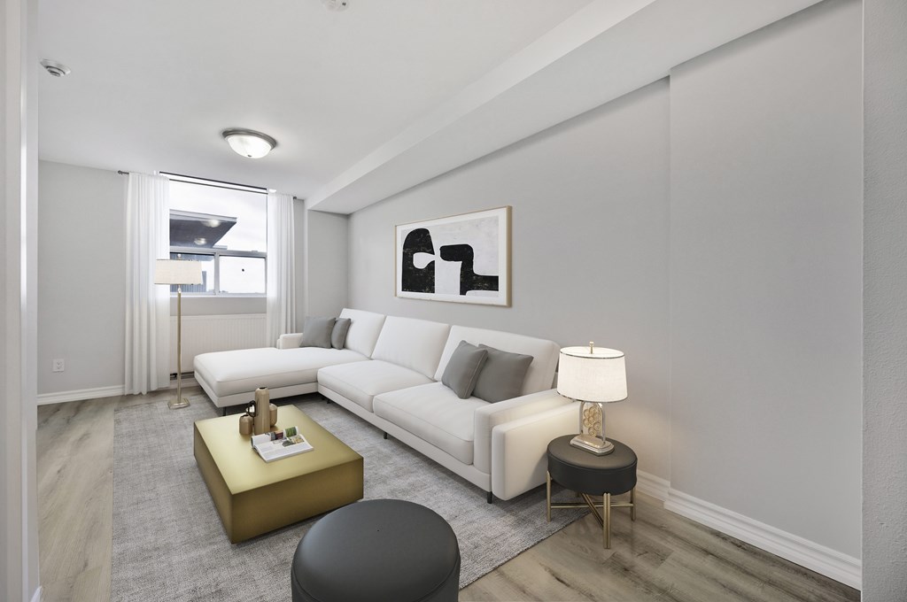A modern living room with a white sofa, a gold side table, and a grey ottoman.