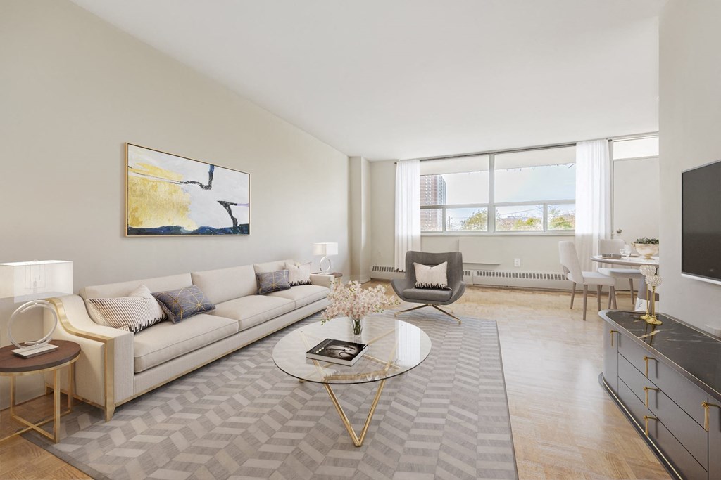 A modern living room with a white sofa, a coffee table, and a painting on the wall.