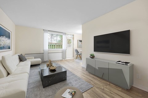 A living room with a white couch, a black coffee table, and a flat screen TV mounted on the wall.