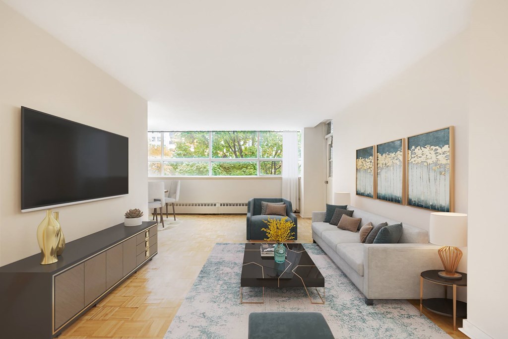 A living room with a grey couch, a black television, and a wooden floor.