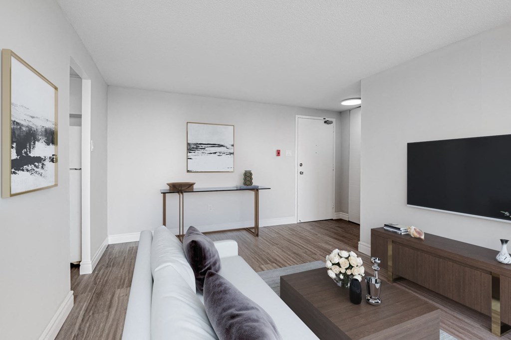 A grey cat is sitting on a grey sofa in a white room.