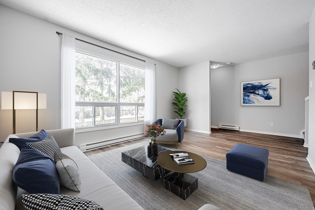 A living room with a white couch, a coffee table, and a large window.