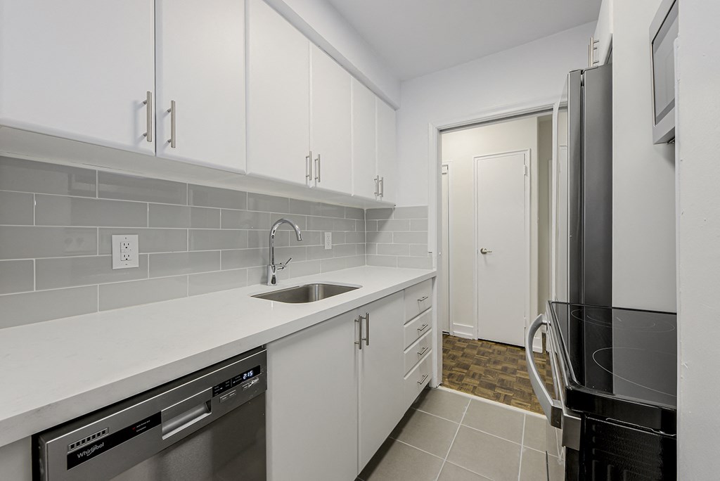 a kitchen with white cabinets and a sink and a refrigerator