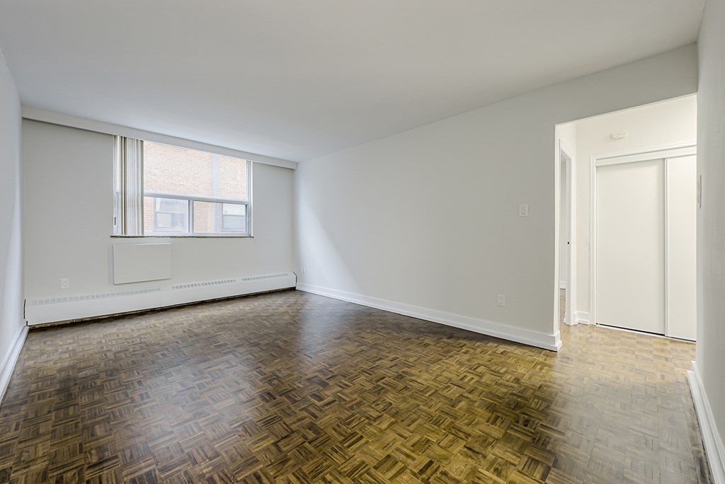 an empty living room with wood flooring and a window