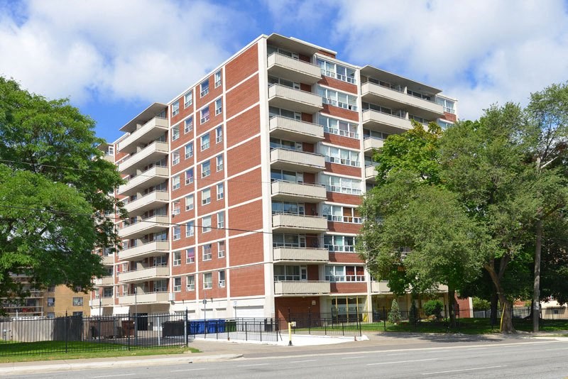 A large red brick apartment building with trees in front.