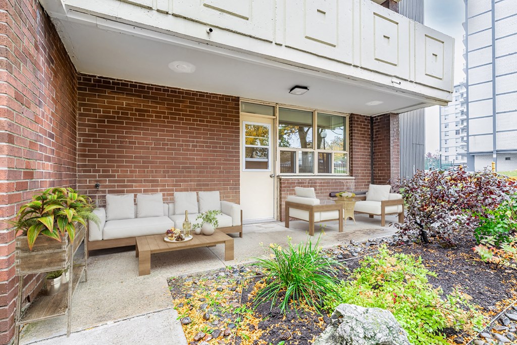 A patio with a table and chairs is surrounded by a brick wall and a garden.