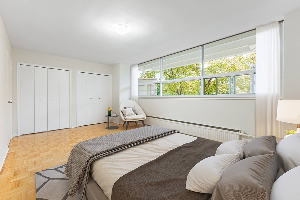 A bedroom with a large bed and a chair by the window.