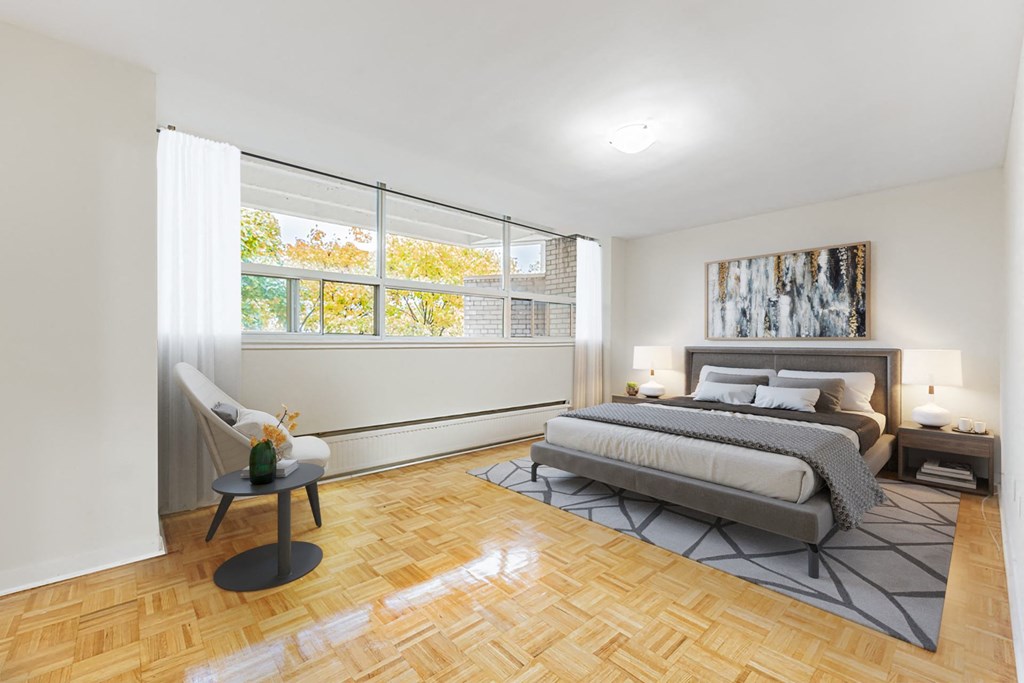 A bedroom with a large bed and a chair by the window.