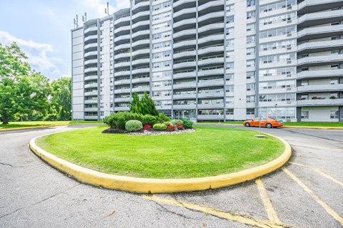 A roundabout with a grassy island in the middle and a building in the background.