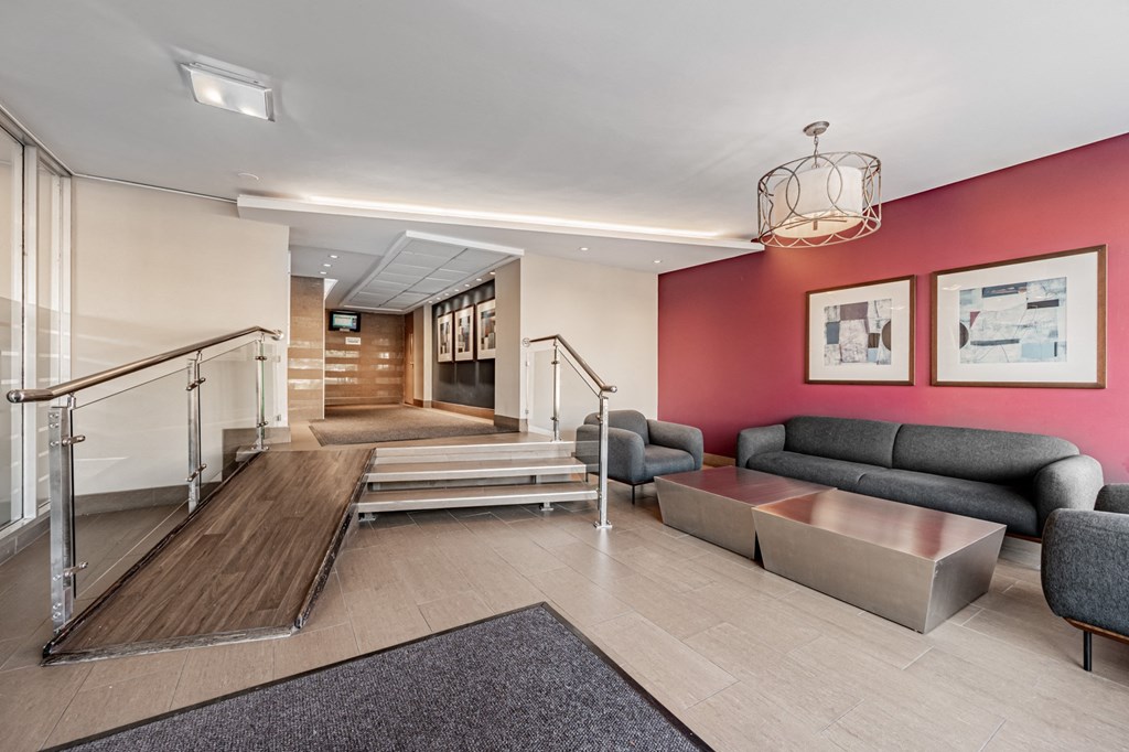 A living room with a grey couch and a red wall.