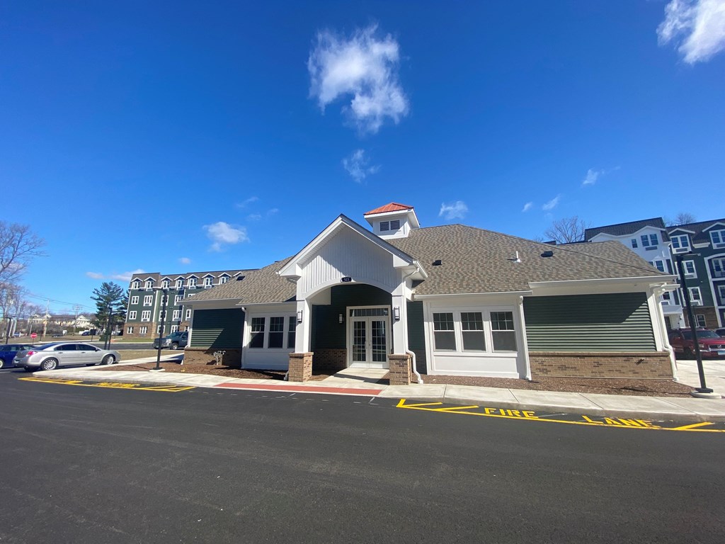 A building with a white front and a red roof is in front of a blue sky.