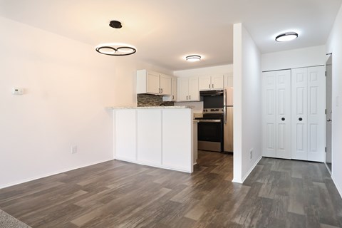 A kitchen with white cabinets and a wooden floor.