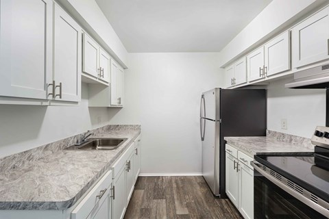 A kitchen with white cabinets and a marble countertop.