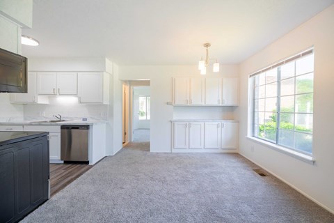 A spacious kitchen with white cabinets and a dark countertop.